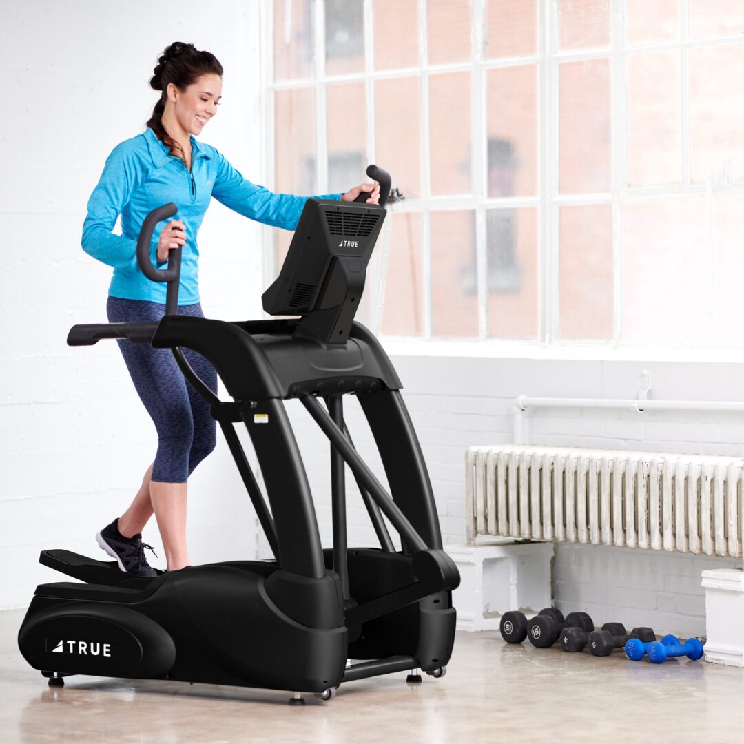 Woman working out on the True Fitness Performance Series Elliptical in a bright home gym