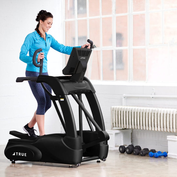 Woman working out on the True Fitness Performance Series Elliptical in a bright home gym